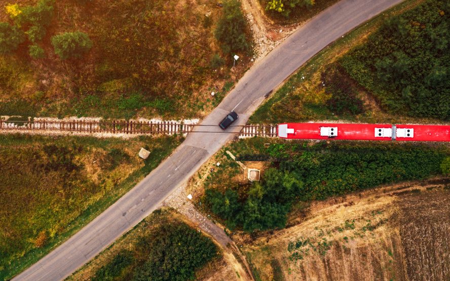 Aerial view of car and train on road junction